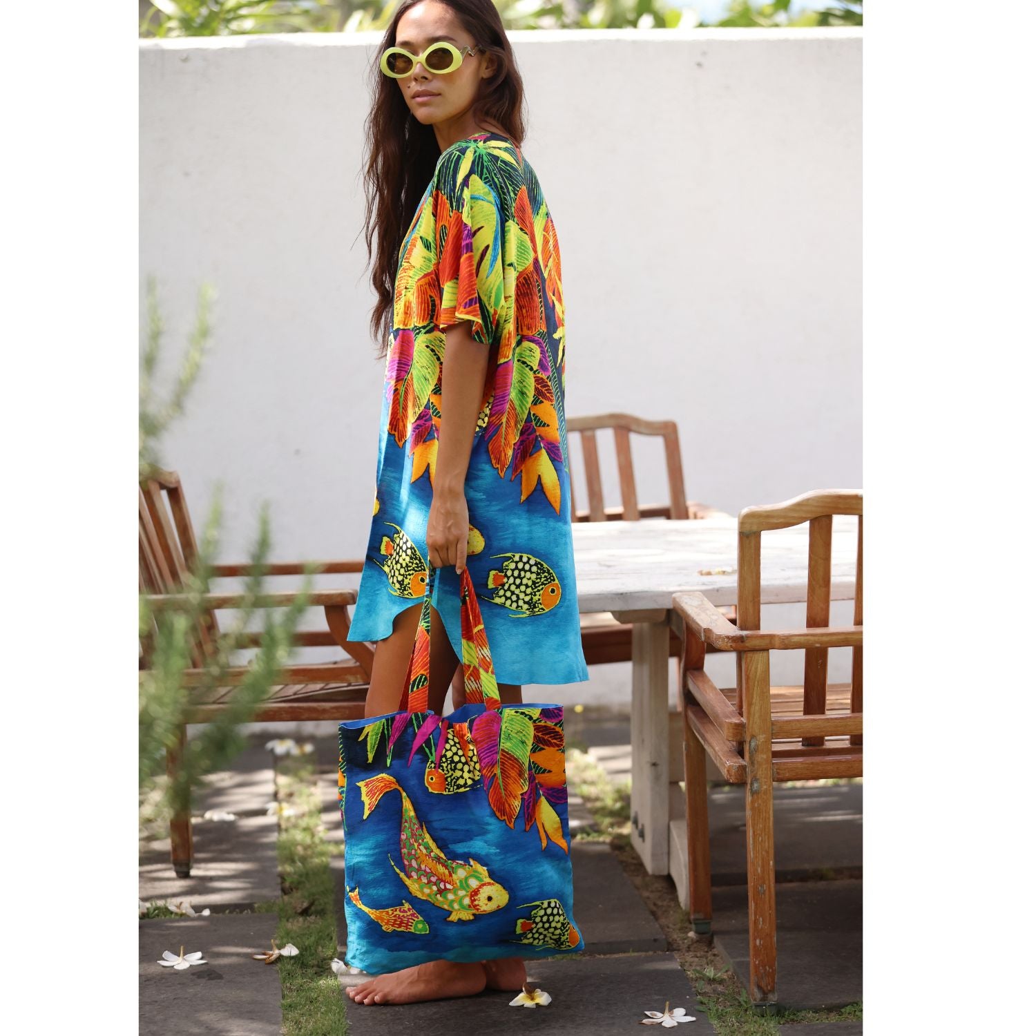 Femme portant une robe colorée et un sac cabas assorti, en extérieur.