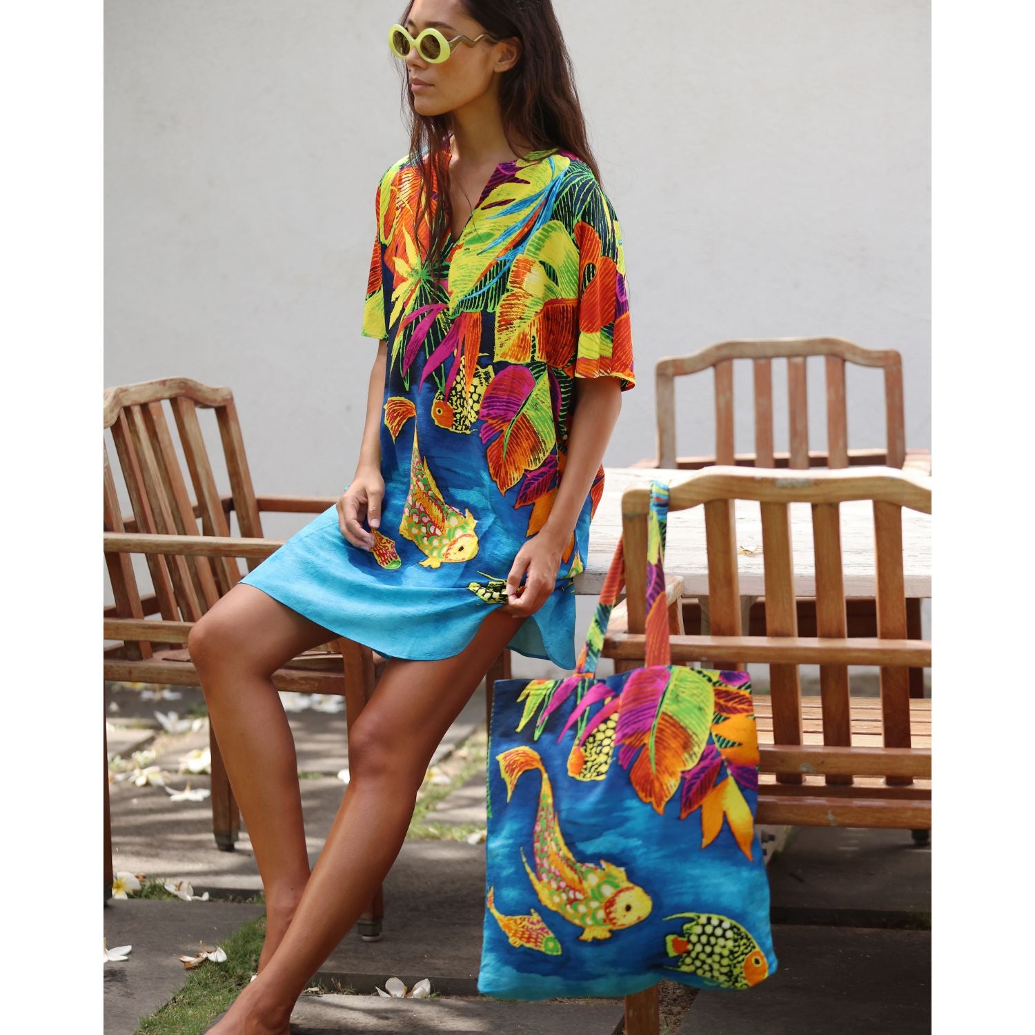 Femme en robe colorée tenant un sac fourre-tout assorti à l'extérieur
