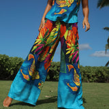 Person wearing colorful tropical-themed pants and top outdoors on a sunny day.