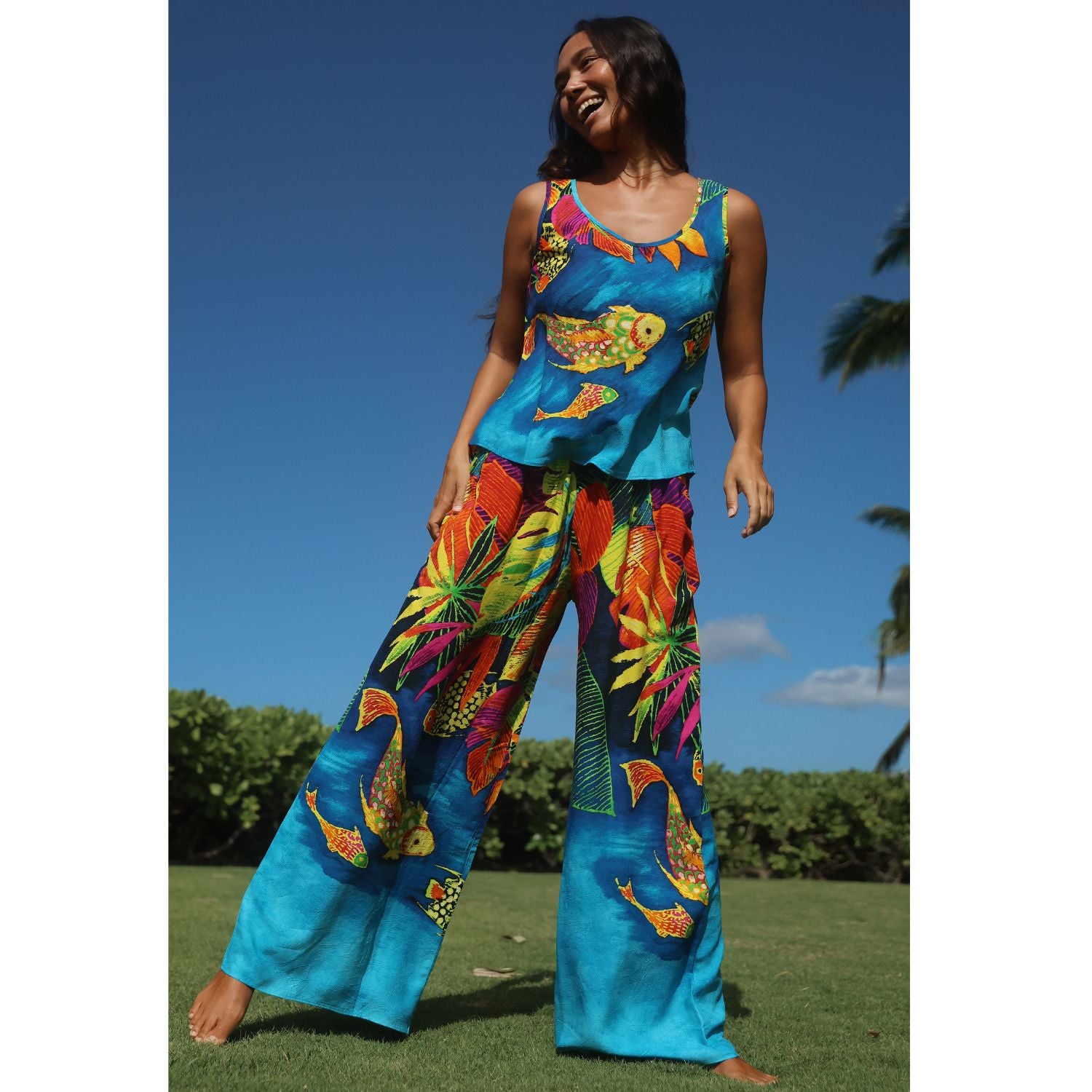 Woman wearing a colorful tropical outfit with fish and floral patterns outdoors.