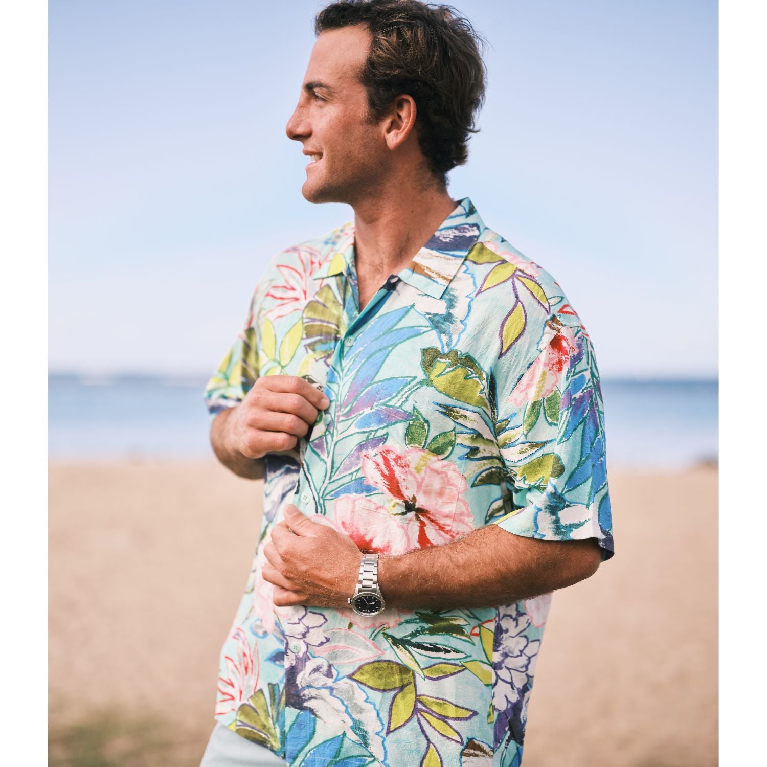 Man wearing a colorful floral shirt on a beach