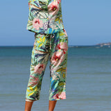 Person wearing a colorful floral outfit standing by the ocean.