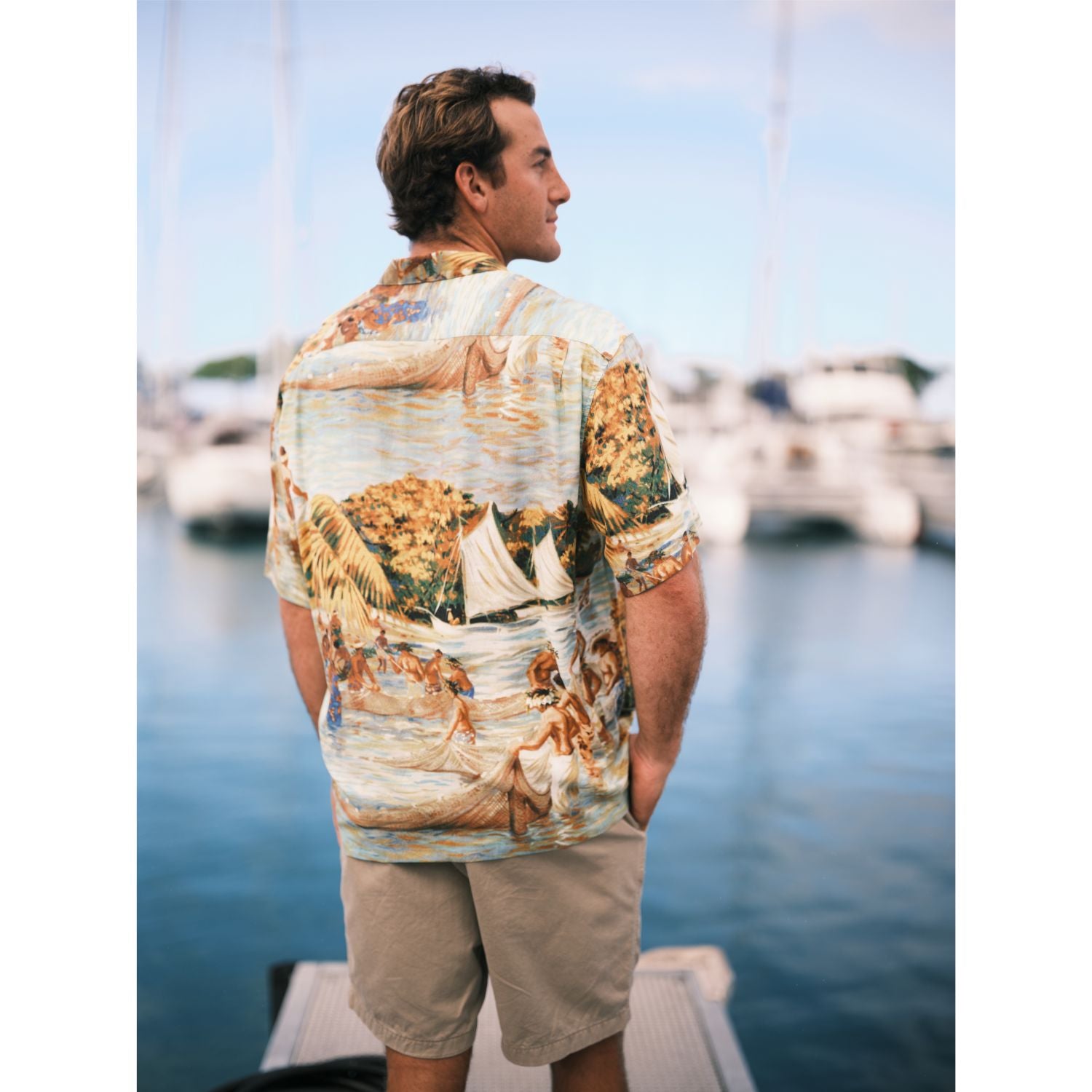 Scenic net fishing scene in the islands button down aloha shirt on model standing on pier.