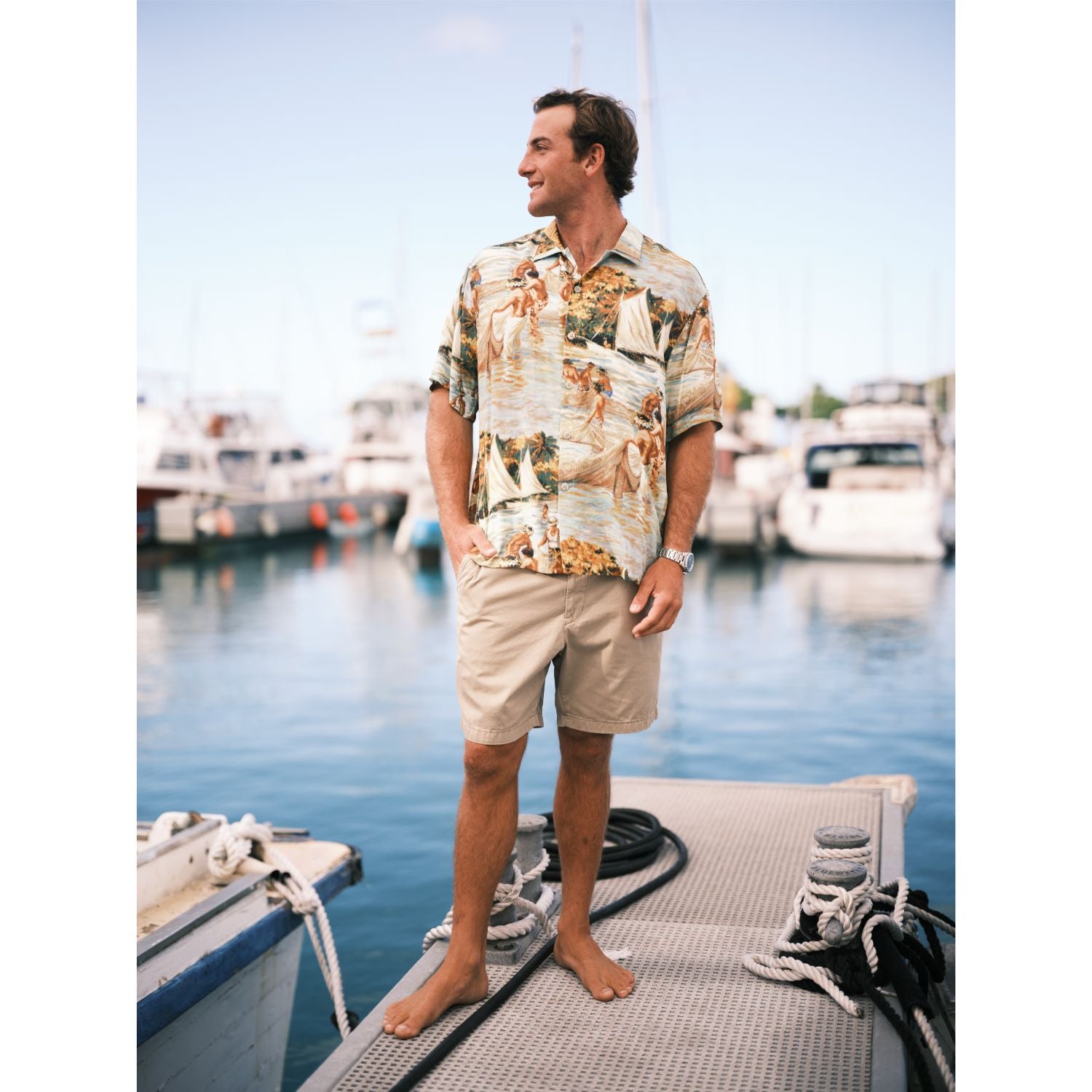 Scenic net fishing scene in the islands button down aloha shirt on model standing on pier.