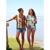 Women wearing a colorful floral shirt and denim shorts in an indoor setting.