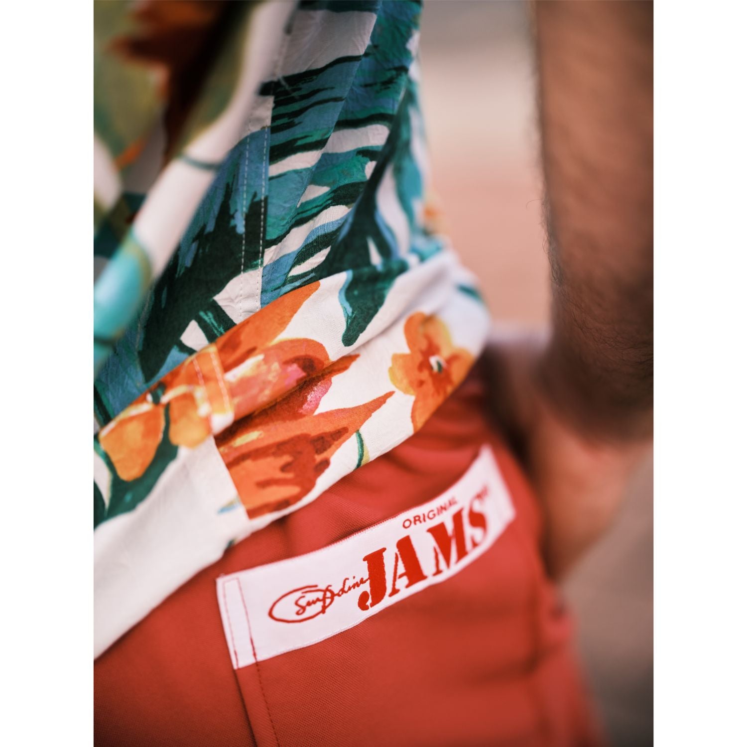 Model standing on walk way with solid red shorts with a Original Jams Label on back pocket