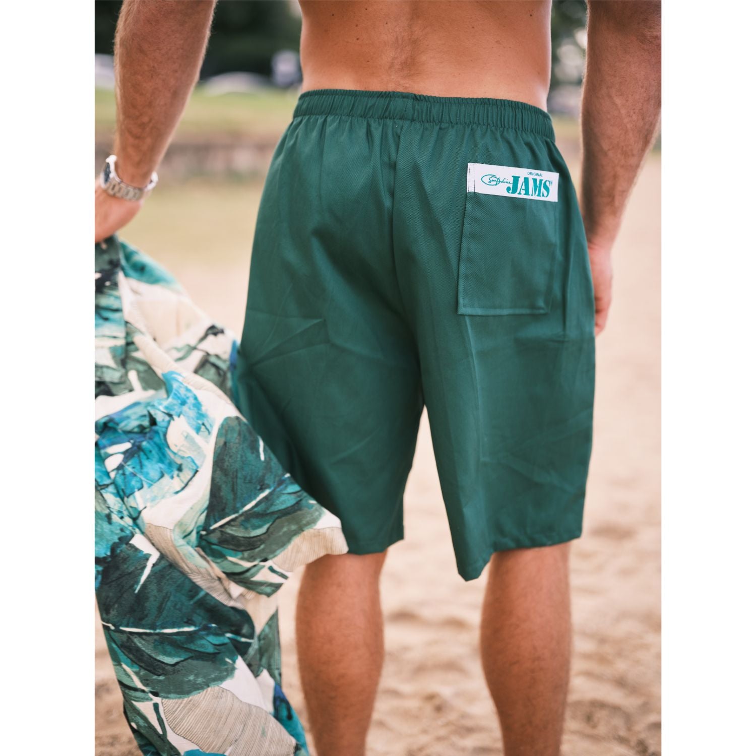 Green shorts with a brand logo on a blurred beach background