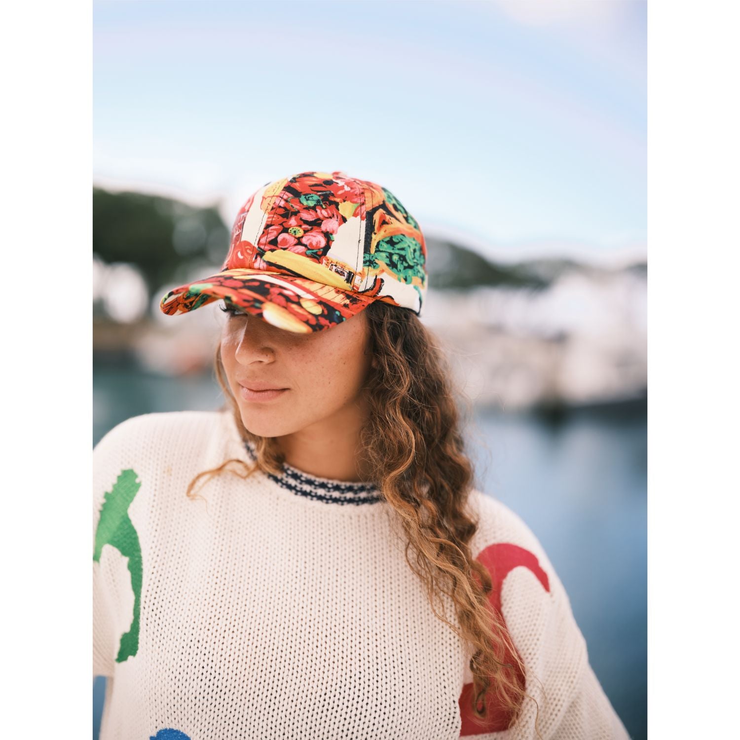 Colorful cap in our Jams World Salsa print on model standing on boat docked at pier.