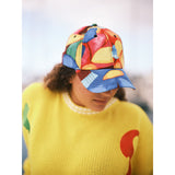 Person wearing a colorful cap and yellow sweater with a red design.