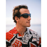 Hombre con gafas de sol y camisa estampada con fondo borroso