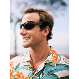 Hombre con gafas de sol y camisa estampada con fondo borroso