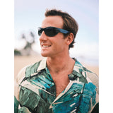 Man wearing sunglasses and a patterned shirt with a blurred background