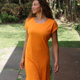 Woman wearing an orange dress standing outdoors on a sunny day.