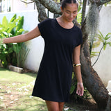 Woman wearing a black dress standing outdoors with greenery in the background
