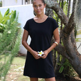 Woman in a black dress holding a white flower in a garden setting