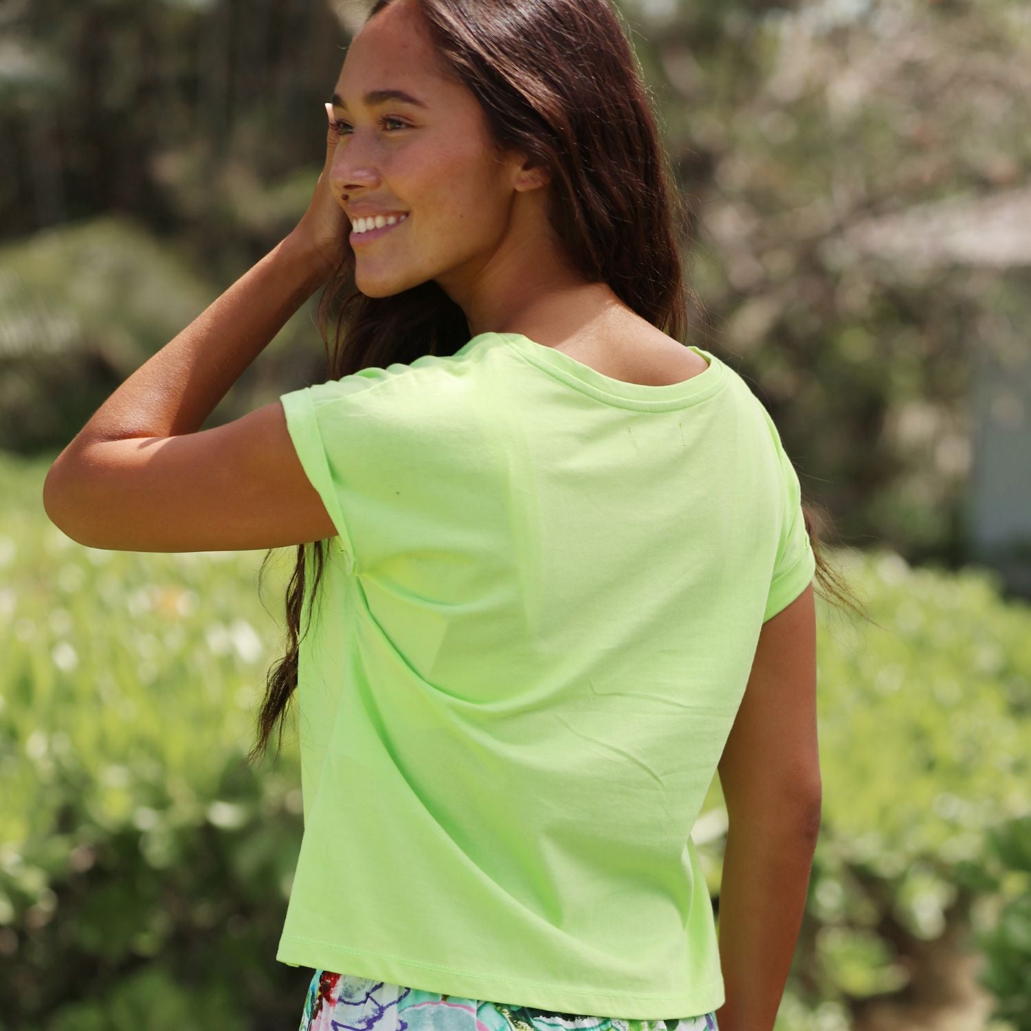 Woman wearing a bright green shirt outdoors with a blurred natural background