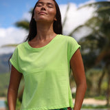 Woman wearing a bright green shirt with a blurred natural background