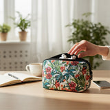 Estuche de viaje con estampado floral con auriculares sobre un escritorio, mano extendiéndose hacia adentro