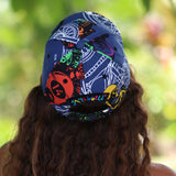 A person viewed from behind wearing a blue swim cap with a colorful graphic print featuring cartoon characters and the text 'KYMOR' and 'SWIM WORLD'.