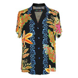 A  short-sleeve button-up shirt with a black base and a vibrant, multicolored tropical print featuring orange, yellow, green, and blue motifs, displayed on a clean white background.