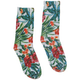 A pair of crew socks with a vibrant tropical floral and leaf print on a white background, featuring red hibiscus flowers, orange blossoms, and green palm leaves.