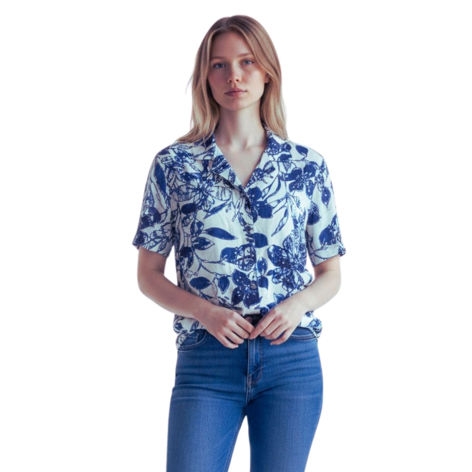 A woman modeling a short-sleeve button-up shirt with a blue floral print on a white background, paired with blue jeans, against a plain white studio background.
