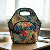 A structured insulated lunch bag with a colorful starfish and coral print sits on a wooden table in a softly lit indoor setting.