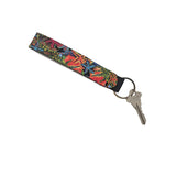 A fabric keychain with a vibrant, multicolored floral pattern in red, blue, yellow, and green, attached to a silver metal key ring and key.