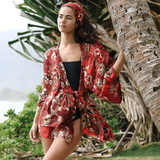 Woman in a red patterned kimono standing next to a palm tree