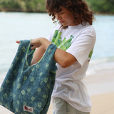 Person holding a green patterned bag by a body of water