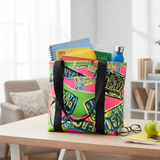 Colorful tote bag with school supplies on a table in a room.