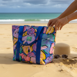 沙滩上摆放着一个色彩鲜艳、印有花卉图案的手提包。