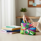 Person holding a colorful pencil case with notebooks and pens on a desk.