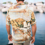 Person wearing a colorful beach-themed shirt by a waterfront