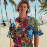 Man wearing a colorful floral shirt on a beach with palm trees in the background