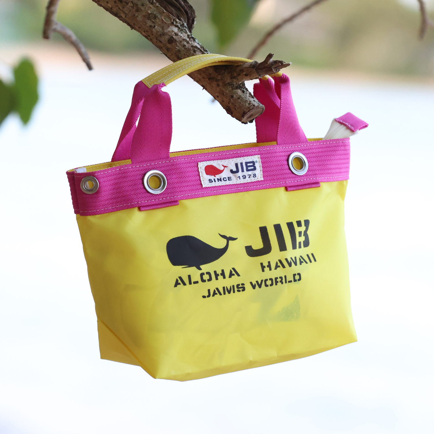 Yellow bag with pink handles hanging on a tree branch