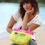 Woman holding a yellow and pink bag with branding on a beach