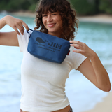 Person holding a blue pouch with branding by a body of water