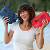 Woman holding two pouches, one blue and one red, with a beach background