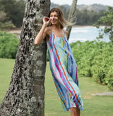 Woman in a colorful striped dress standing next to a tree with a scenic background
