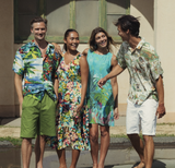 Four people wearing colorful tropical outfits standing together outdoors.