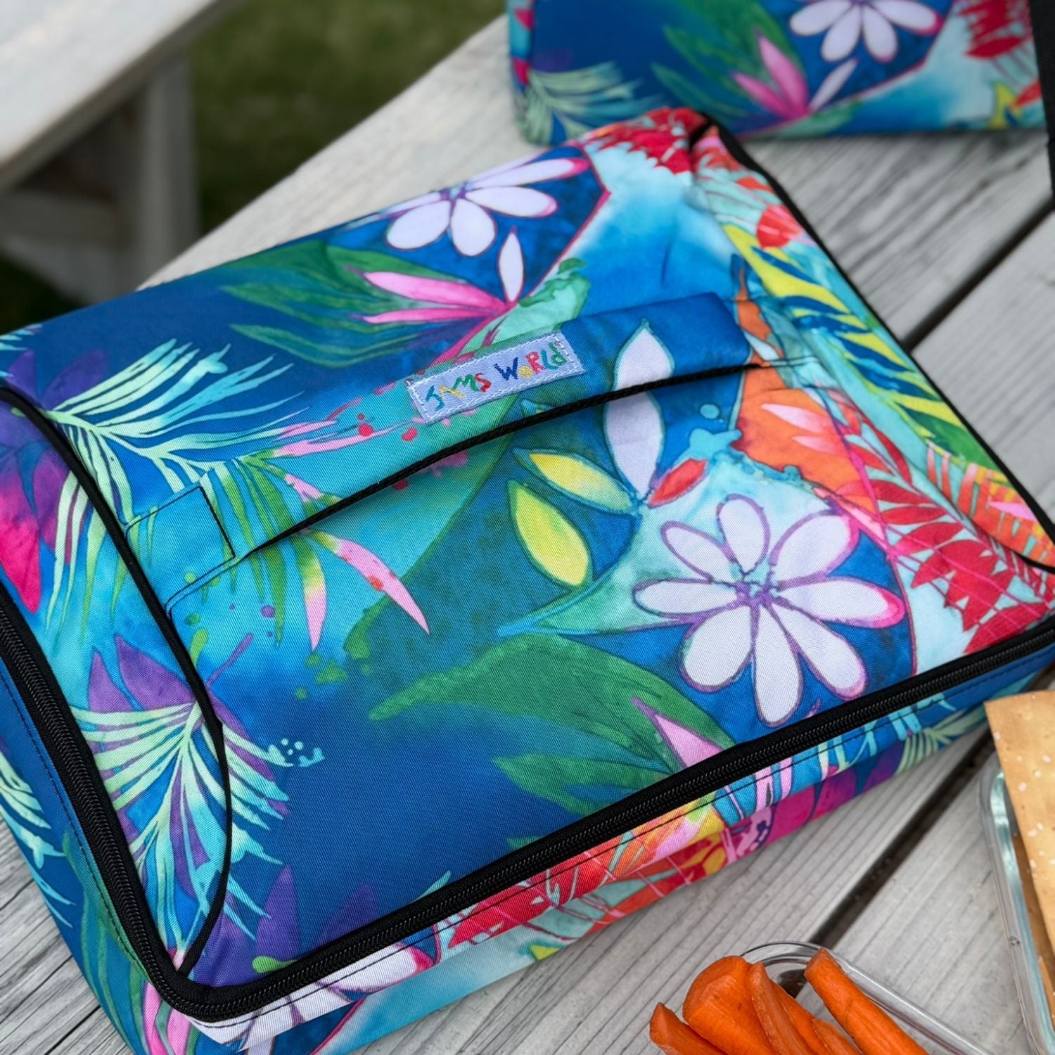 Bolsa térmica con estampado floral de colores sobre una superficie de madera.