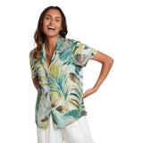 Woman wearing a tropical leaf patterned shirt on a white background